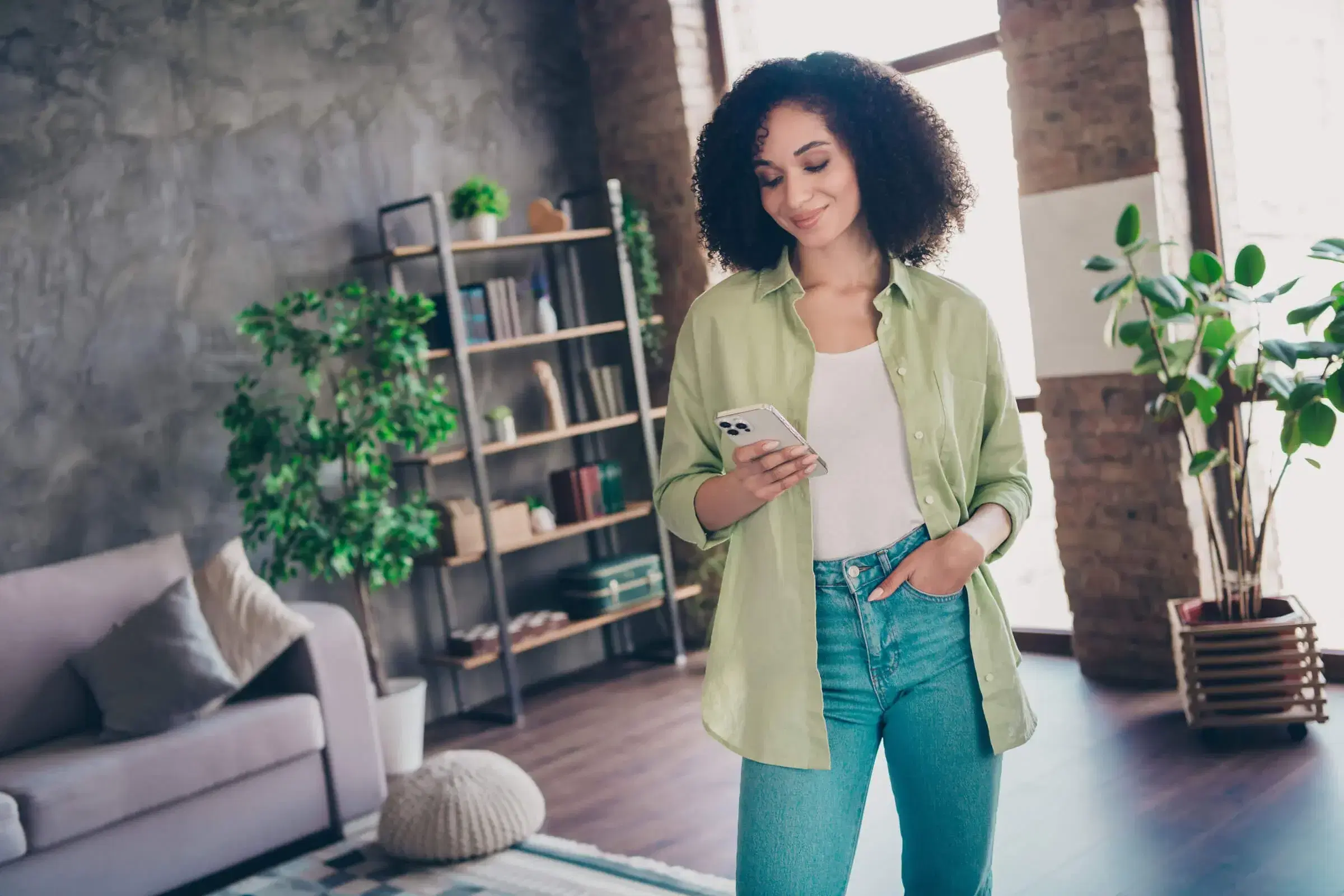 A person reviewing their finances on a phone in a bright living room